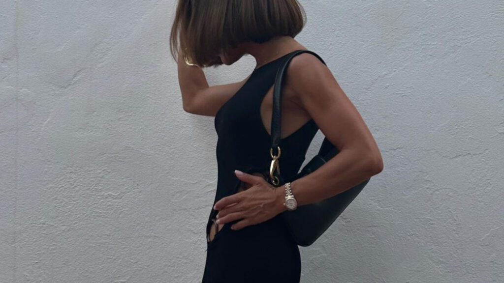 Una mujer de cartera y vestido negro caminando