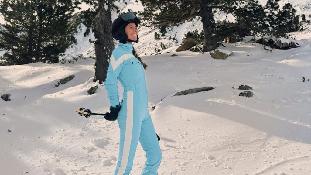 Una mujer usando un traje de esquiar de color azul celeste para pasear el terreno nevado