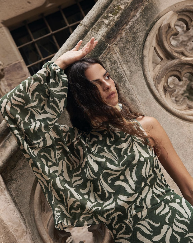 Una mujer luciendo un elegante vestido verde con petalos blancas