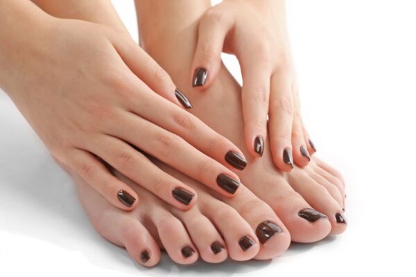 Una mujer acerca sus manos a sus pies para mostrar que todas sus uñas estan pintadas de negro