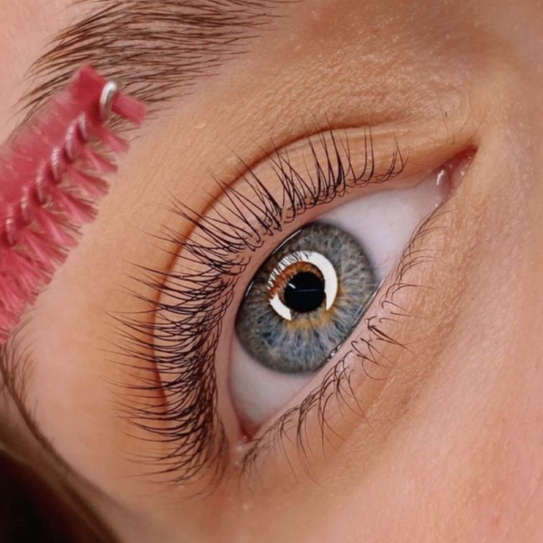 El ojo derecho de una señora observando un peine para cejas acercándose a sus cejas