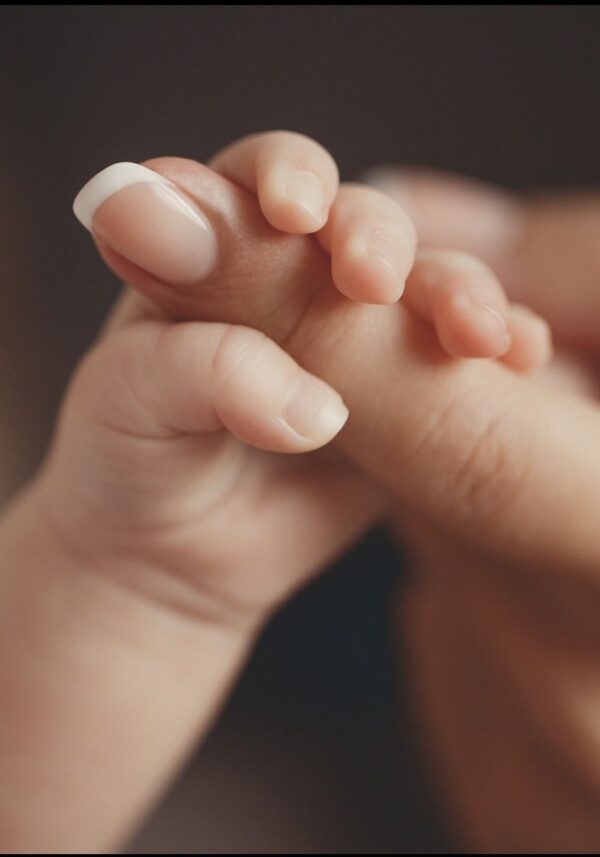 La mano de una bebe sosteniendo el dedo de su madre