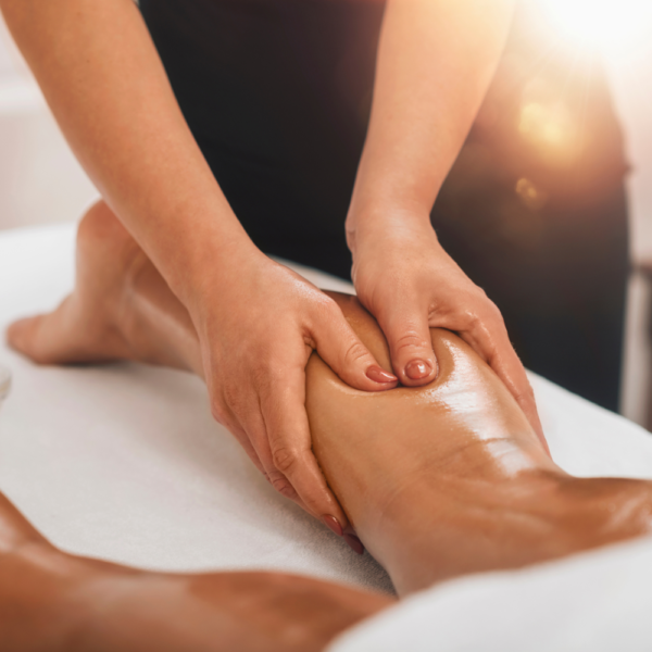 Un especialista masajeando las piernas con un aceite o crema al paciente